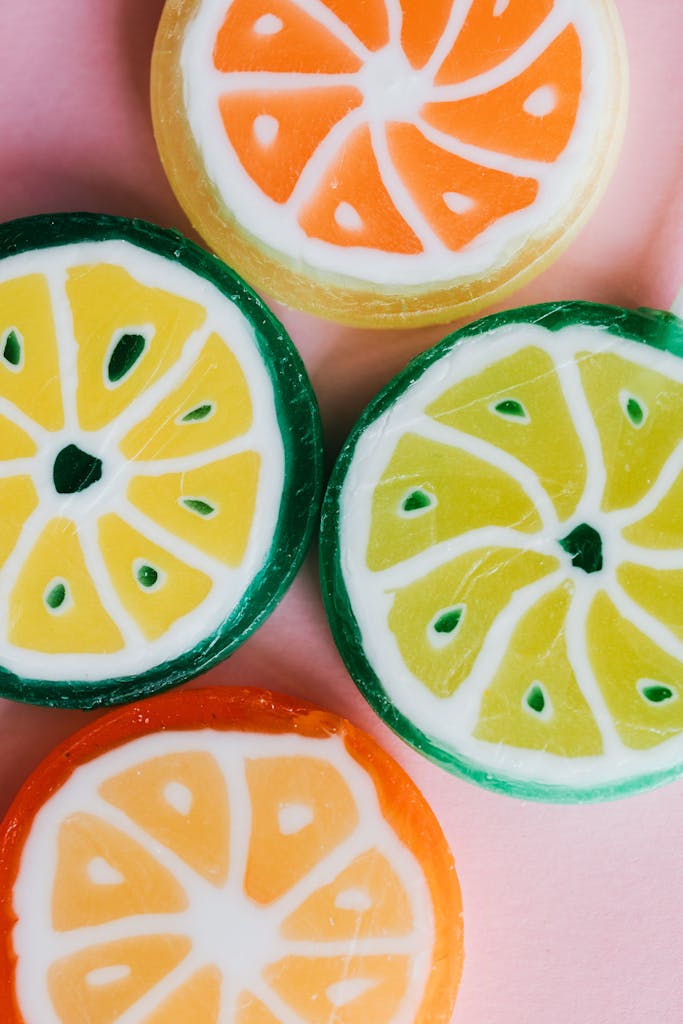 Vibrant close-up depicting colorful citrus-inspired candies on a pink background.